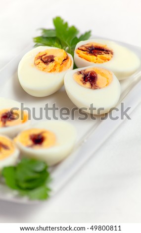 A dish of hard-boiled eggs with balsamic vinegar on the yolks and fresh parsley