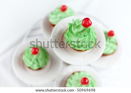 Carrot cupcakes with green whipped cream frosting and a candied cherry on top.