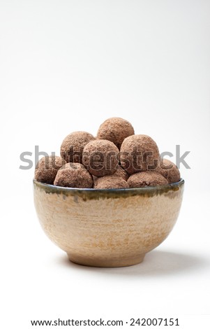 Chocolate truffles with cocoa, nuts, dried fruit, figs and honey for a healthy diet, fasting and vegetarianism in a bowl on an isolated background