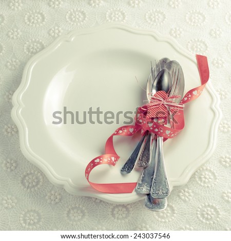 white plate with cutlery, tied with a red ribbon for a romantic dinner couples in love on Valentine's Day or wedding