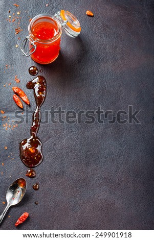pepper sauce in the pot and drop of sauce on a background of dark skin