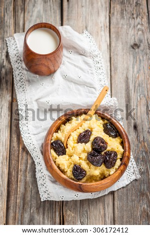 Millet milk porridge with plums on a wooden background. Russian kitchen