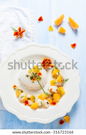 Fish in citrus sauce with rice. Cod with tangerines and marigold flowers