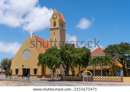 St. Bernard Church (Parokia San Bernardo) Catholic Church in Kralendijk, Bonaire, Caribbean Netherlands. Yellow church with cross, tall clock and bell tower, statue of St. Bernard in a brick niche. Foto d'archivio © 