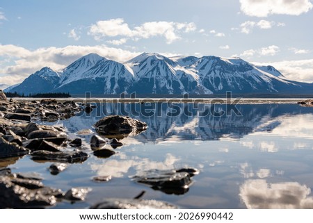 Stunning view of the Atlin Mountains in northern British Columbia during spring time on perfect blue sky day with clouds and reflection in calm water below. Scenic, view for home, office art.  Foto stock © 