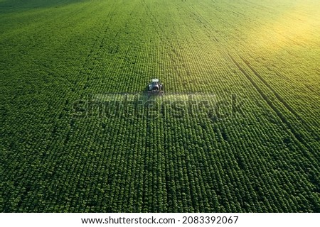 Taking care of the Crop. Aerial view of a Tractor fertilizing a cultivated agricultural field. Imagine de stoc © 