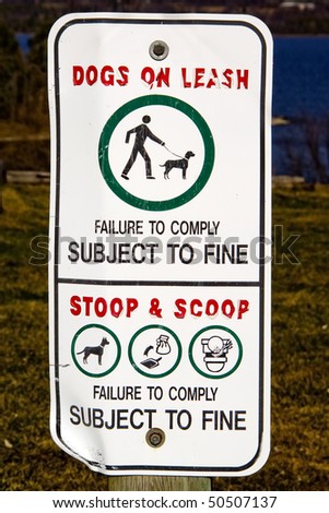 A sign warning to keep dogs on a leash and owners to clean up their dog\'s messes, or face a fine.