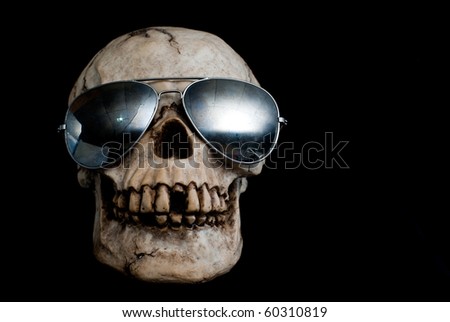 An old, human skull wearing mirrored aviator type sunglasses.