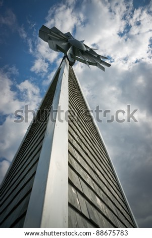 Unusual perspective of a tall, wooden windmill under a cloudy blue sky