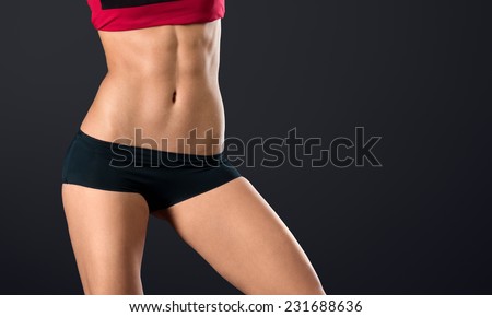 Pretty woman\'s torso close up with strong and perfect abs on black background