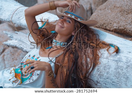 Happy young woman lying on rock. Boho style