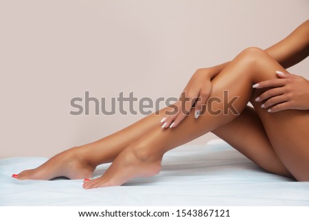 Woman body care. Close up of long female tanned legs with perfect smooth soft skin, pedicure, healthy nails on white background. Epilation, beauty and health concept
 Imagine de stoc © 