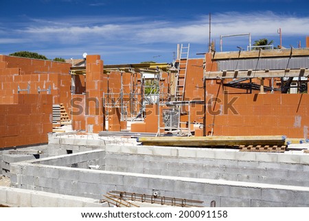 Construction work. Building of red brick cottage on blue sky background