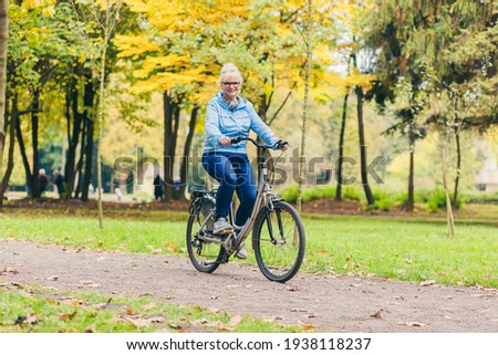 Similar – Image, Stock Photo Middle aged woman riding his electric scooter and looking at mobile phone.