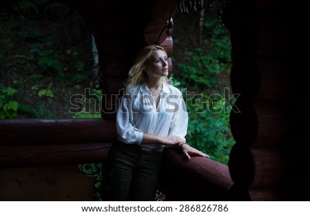 Beautiful woman standing on the porch of a wooden house