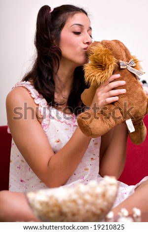 cute little Girl eating popcorn and watching tv with her teddy bear