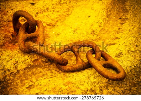 Detail of an old rusty metal chain anchored to a concrete block - toned image