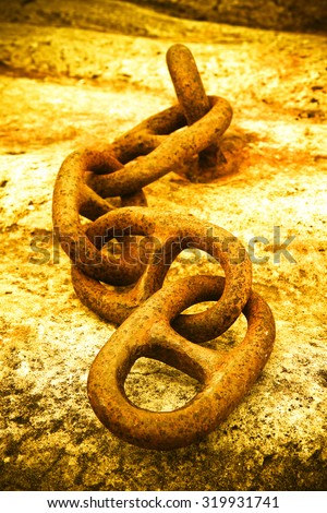 Detail of an old rusty metal chain anchored to a concrete block - toned image