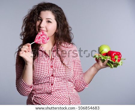 Female vegetarian with vegetables and candy on the background