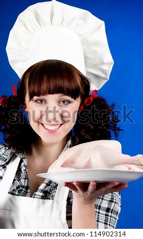 Smiling happy cook woman holds a Crude hen and knife