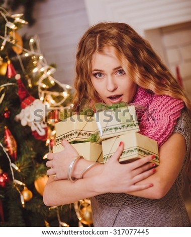 Young girl near a new-year tree with gifts and candles