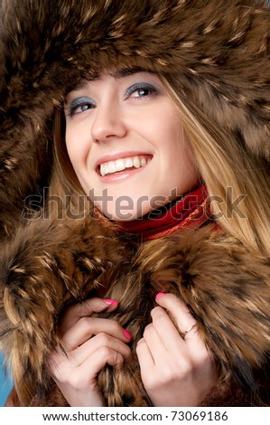 Close-up portrait of young beautiful girl wearing fur-cap and smiling