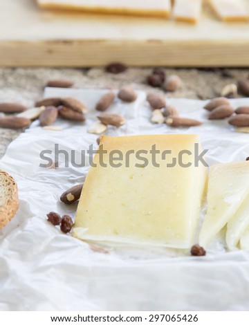Close up of pieces of cheese and roasted almonds on a stone table. Rustic lunch of cheese and almonds