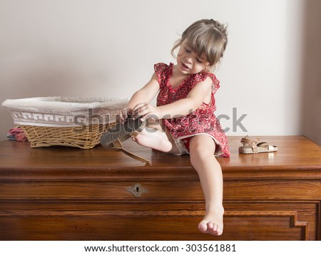 Little girl trying to put on her shoes. Indoor portrait with blank space to put your own text