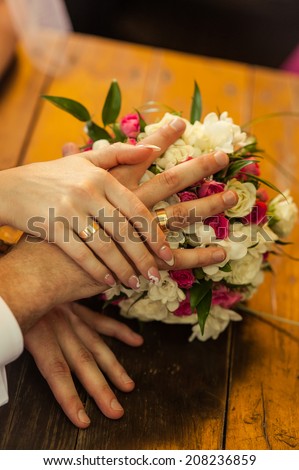 The hand holding the bride's ring on a wooden table