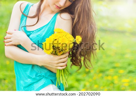 beautiful girl in a Sunny summer day walking in the garden and keeps yellow dandelions in the hands