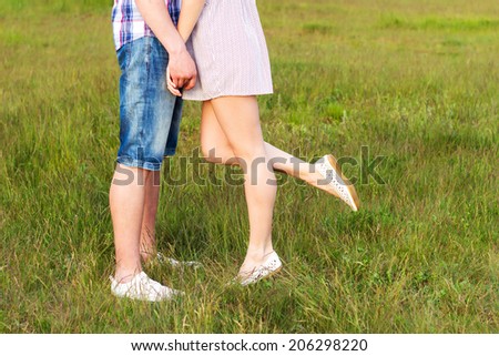 Young happy couple kissing in love, standing on the grass in the summer sun the night