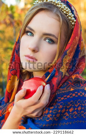 beautiful young sweet girl in a headscarf with the rim on the head with a red Apple in his hand, like a fairy tale character with blue eyes