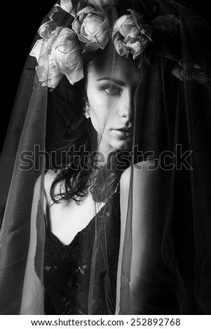 black and white portrait of a beautiful sexy girl with black hair in a black lace dress with a wreath on his head covered with a veil in the Studio on a black background, beauty portrait
