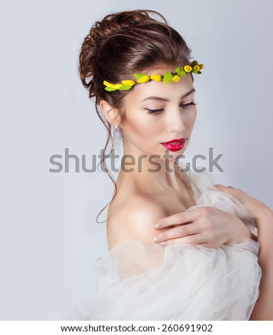 beautiful young sexy elegant woman with red lips, beautiful hair with a wreath of yellow roses on the head with bared shoulders, the way for the bride at a wedding