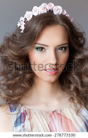 Smiling gentle elegant young beautiful girl with lush hair with a rim of bright colors