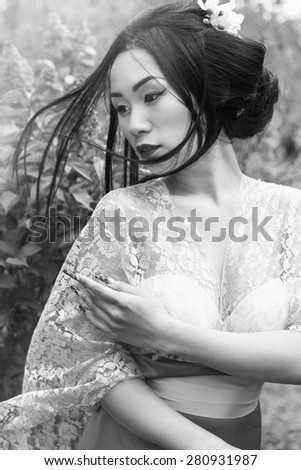 Chinese beautiful sexy girl in a kimono with a beautiful makeup with hair walking in a garden near blooming lilac bushes