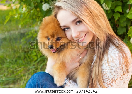 Happy beautiful gentle girl hugging her pet dog red Spitz