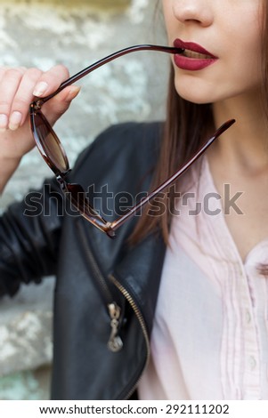 girl with red lipstick in a black leather jacket sunglasses bit in city