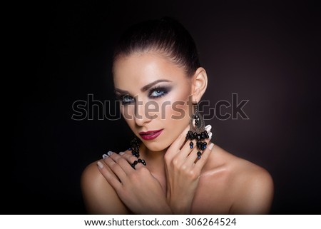 expensive jewelry wreath earrings and ring on a beautiful sexy nude elegant brunette girl with bared shoulders with bright evening make-up