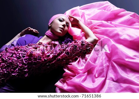 Beautiful caucasian woman in pink elegant dress on black background. Studio shot