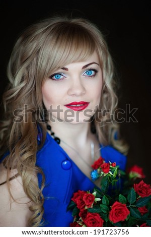 Portrait of beautiful smiling woman isolated on black studio shot in blue dress with rose