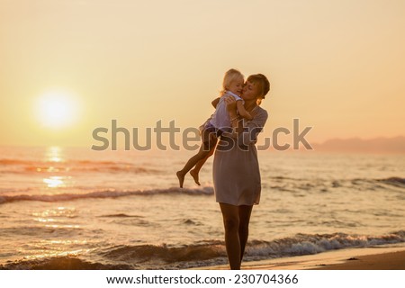 Happy mother kissing her daughter on the beach at sunset, summer time. Italy, Forte dei Marmi