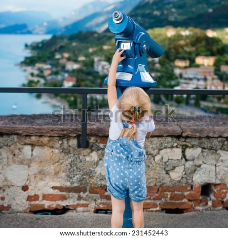 little girl looking through telescope at  viewpoint in lake Garda, Italy