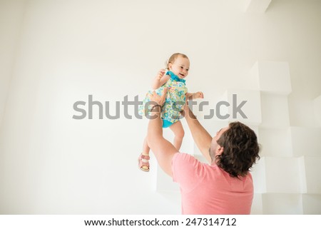 father throws up in the air a beautiful little girl on a white background