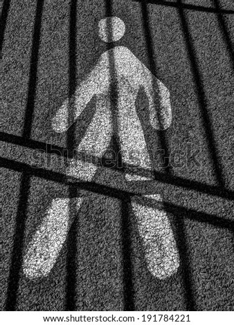 Prisoner walking inside his asphalt cell behind bars