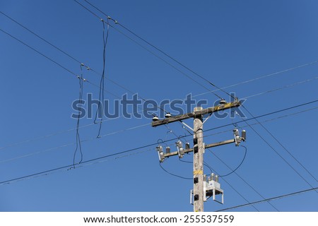 Power lines running down to a wooden telephone pole in San Francisco\'s Richmond District.  Deep clear blue sky.  Strong diagonals.