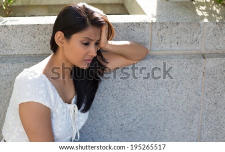 Closeup portrait, dull upset sad young woman in white dress sitting on bench, really depressed, down about something, isolated gray background. Negative emotion facial expression feeling body language