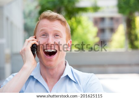 Closeup portrait, young happy ecstatic man with wide open mouth talking on cell phone, isolated outdoors background
