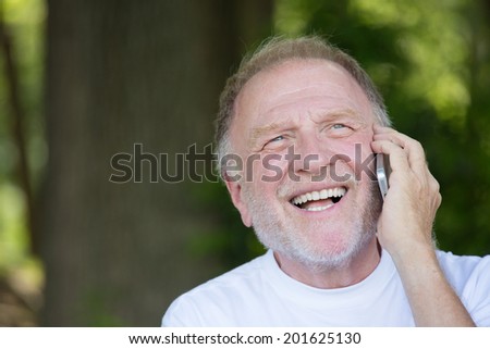 Closeup portrait, older, happy ecstatic man with wide open mouth talking on cell phone, isolated outdoors background