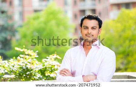 Closeup portrait, happy handsome man in pink shirt, arms folded, crossed, standing outside of his office during sunny day, isolated balcony background of green trees.